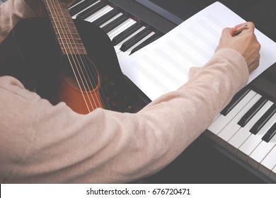 Male Songwriter Writing Song On Blank Music Sheet