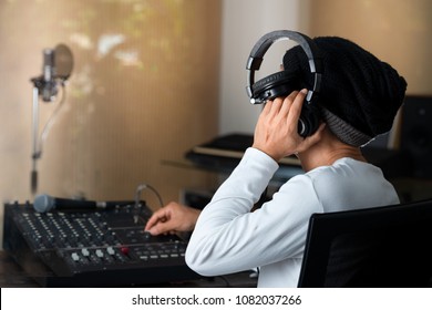 Male sound engineer hipster producer listening headphone adjusting and balancing sound of music from digital mixer volume in recording studio.Music producer working in home recording studio. - Shutterstock ID 1082037266