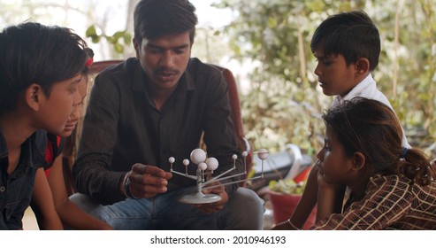 A Male South Asian Teacher Showing Children Educational Toys