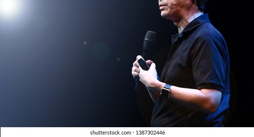 The Male Speaker Is Doing The Public Speaking With The Dark Background Under The Spot Light And Lense Flare, In Concept Of Talk Show, Flare Light, Motivational Speaking, Inspiration Speaker.