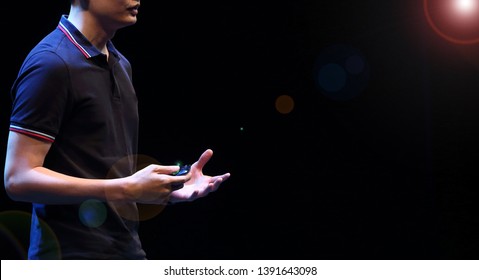 The Male Speaker Is Doing The Public Speaking With The Dark Background Under The Spot Light And Lense Flare, In Concept Of Talk Show, Flare Light, Motivational Speaking, Inspiration Speaker.