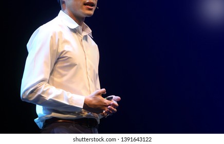 The Male Speaker Is Doing The Public Speaking With The Dark Background Under The Spot Light And Lense Flare, In Concept Of Talk Show, Flare Light, Motivational Speaking, Inspiration Speaker.