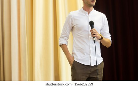 The Male Speaker Is Doing The Public Speaking With The Dark Background Under The Spot Light And Lense Flare, In Concept Of Talk Show, Flare Light, Motivational Speaking, Inspiration Speaker.