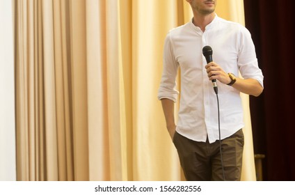 The Male Speaker Is Doing The Public Speaking With The Dark Background Under The Spot Light And Lense Flare, In Concept Of Talk Show, Flare Light, Motivational Speaking, Inspiration Speaker.