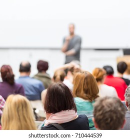 Male speaker giving presentation in lecture hall at university workshop. Audience in conference hall. Rear view of unrecognized participant in audience. Scientific conference event. - Shutterstock ID 710444539