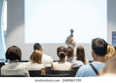 Male speaker giving a talk in conference hall at business event. Audience at the conference hall. Business and Entrepreneurship concept. Focus on unrecognizable people in audience. - Powered by Shutterstock