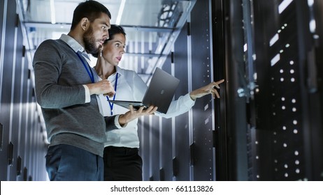 Male IT Specialist Holds Laptop and Discusses Work with Female Server Technician. They're Standing in Data Center, Rack Server Cabinet is Open. - Shutterstock ID 661113826