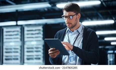Male IT Specialist Walks Between Row of Operational Server Racks in Data Center. Engineer Uses Tablet Computer for Maintenance. Concept for Cloud Computing, Artificial Intelligence, Cybersecurity.