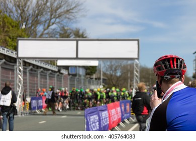 Male Spectator Taking Photo Of The Start Of A Cycling Race