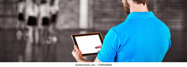 Male sports teacher using digital tablet in basketball court at school gym - Powered by Shutterstock