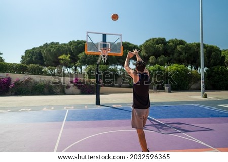 Male sportsman playing basketball throwing the ball at playgroun