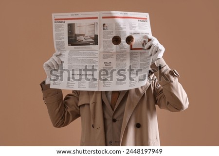 Male spy holding newspaper with holes on brown background