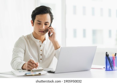 Male staff portrait while listening to the phone while taking notes - Powered by Shutterstock