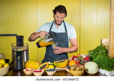 Male staff pouring juice into glass at counter in health grocery shop - Powered by Shutterstock