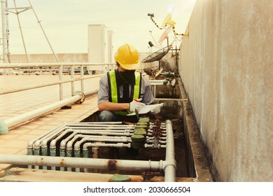 Male staff technician on the condominium rooftop recorded the monthly water usage job number. and inspect the valve fittings for rust to prevent damage to ensure they are ready for use.