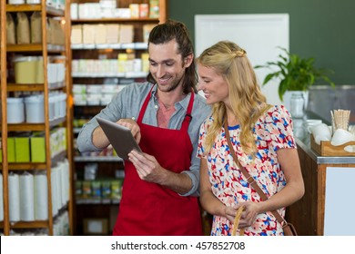 Male staff and woman looking at digital tablet in supermarket - Powered by Shutterstock