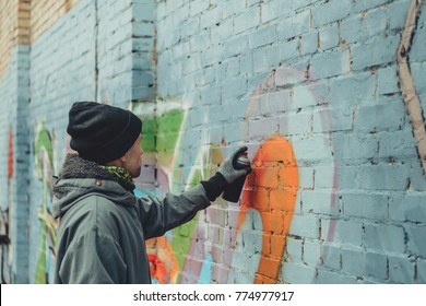 Male Street Artist Painting Colorful Graffiti On Wall