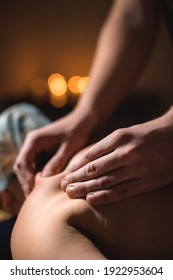 Male Strong Hands Massage Back To Middle Aged Woman In Dark Spa Room By Candlelight