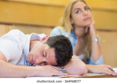 Männlicher Student, der während des Unterrichts an der Universität eingeschlafen ist