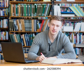 Male student with laptop studying in the university library