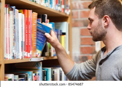 Male Student Picking A Book In A Library