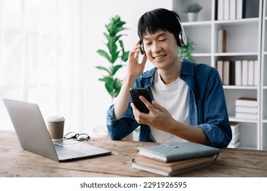male student sitting at the desk using headphones when studying - Shutterstock ID 2291926595