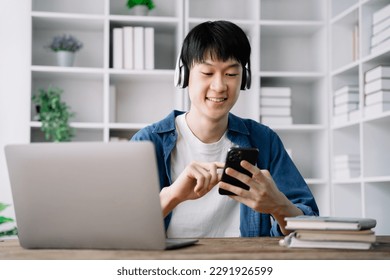 male student sitting at the desk using headphones when studying - Shutterstock ID 2291926599