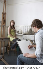 Male Student Sketching Female Model In Art Class