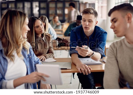 Male student talking to his friends during lecture in the classroom. 