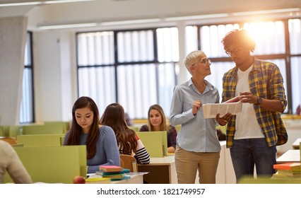 Male Student At The University Classroom Asking Questions About The Lesson To Female Professor 