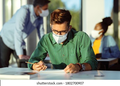 Male Student Wearing Protective Face Mask While Having An Exam At Lecture Hall. 