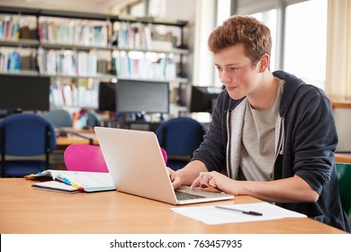 Male Student Working At Laptop In College Library