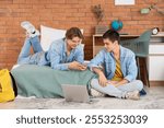 Male students using mobile phone in dorm room