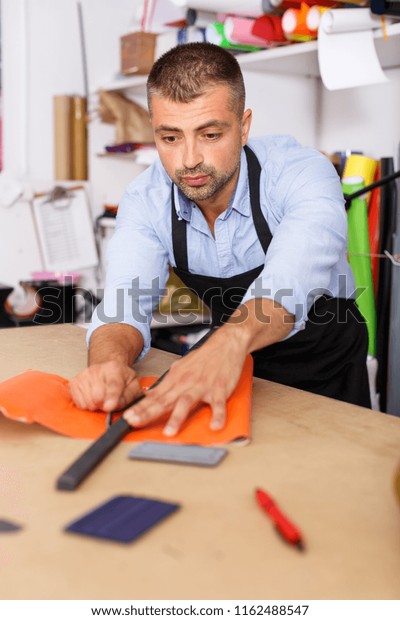 male studio worker\
cuts off colored paper