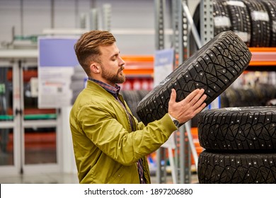 Male Studying Car Tire In Market, Guy In Casual Wear Stand Looking At Tire, Make Choice. Shopping Time