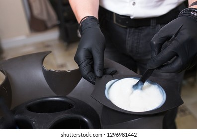 Male Stylist in gloves preparing color cream for dying hairin  a container, a mask for treatment procedure in beauty salon. Hhairdresser mixing brush coloring hair concept supplies. Spa copy space - Powered by Shutterstock