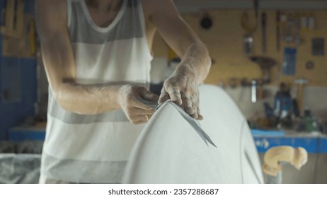 Male surfboard shaper making surfboard in his workshop. Hand shaping from blank. - Powered by Shutterstock