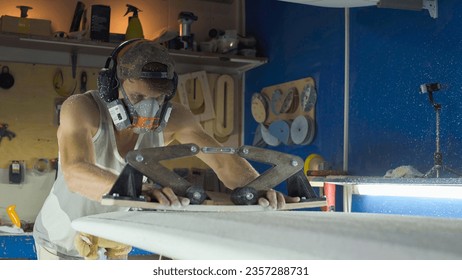 Male surfboard shaper making surfboard in his workshop. Hand shaping from blank. - Powered by Shutterstock