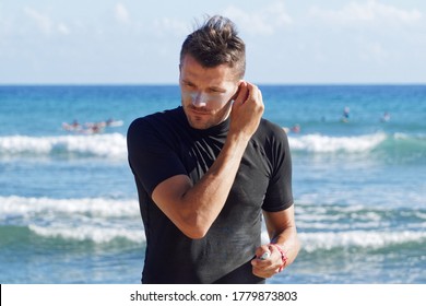 Male Surfer Putting Sunscreen Cream On Ear. 