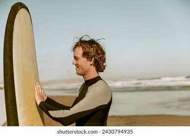 Male surfer in wetsuits standing with surfboard and preparing for ride on waves - Powered by Shutterstock