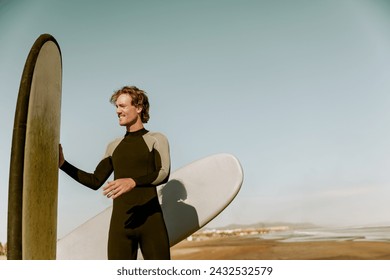 Male surfer in wetsuits standing with surfboard and preparing for ride on waves - Powered by Shutterstock