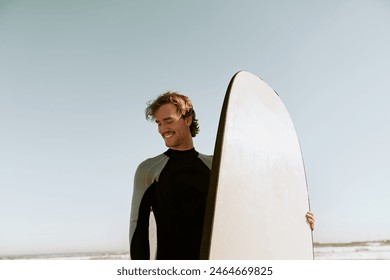 Male surfer in wetsuits standing with surfboard and preparing for ride on waves - Powered by Shutterstock