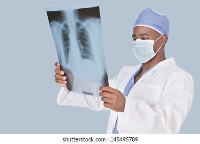 Male surgeon analyzing x-ray report over light blue background