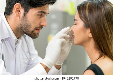 Male Surgeon Examining Young Asian Female's Face In Modern Clinic ,concept For Beauty Clinic Business