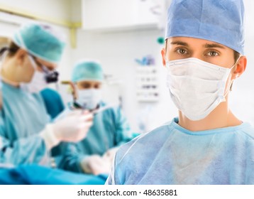 Male surgeon with two doctors on background in operation room - Powered by Shutterstock