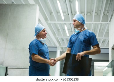 Male surgeons holding x-ray while shaking hands in hospital. Healthcare workers in the Coronavirus Covid19 pandemic
