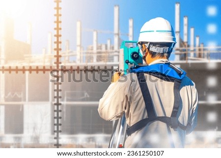 Male surveyor. Guy with geodetic instrument. Builder with back to camera. Geodetic equipment. Optical theodolite in hands engineer. Geodetic surveys during construction. Building under construction