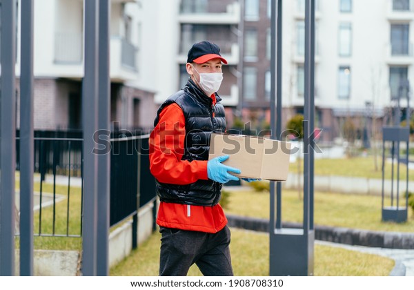 The male sweden\
delivery staff held a customer\'s paper box or box. Delivery workers\
wear protective masks and protective gloves. Contactless delivery\
service concept.