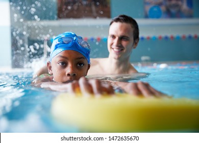 Male Swimming Coach Giving Boy Holding Float One To One Lesson In Pool - Powered by Shutterstock