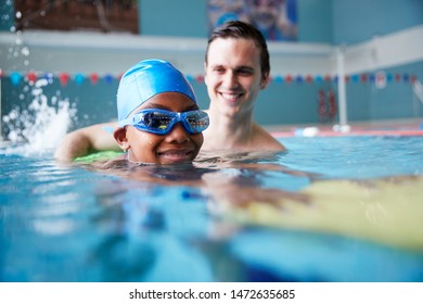 Male Swimming Coach Giving Boy Holding Float One To One Lesson In Pool - Powered by Shutterstock